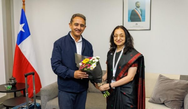 Kirtivardhan Singh receiving flowers beside the flag of Chile