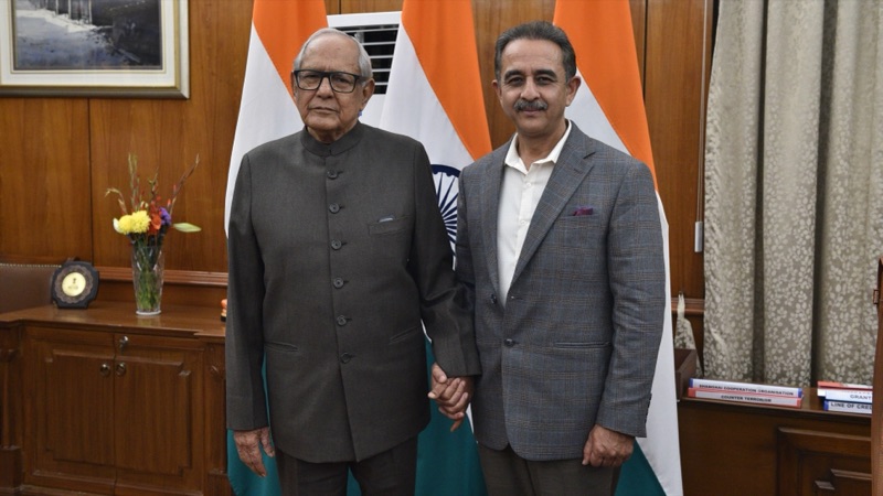 Kirtivardhan Singh standing with an elderly man in an office with Indian flags