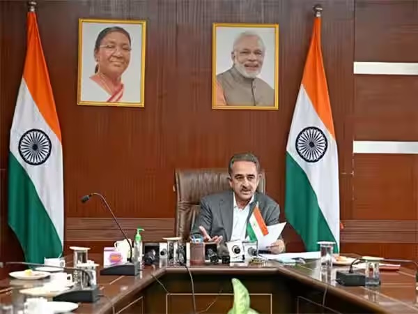 Kirtivardhan Singh at a conference table between Indian flags